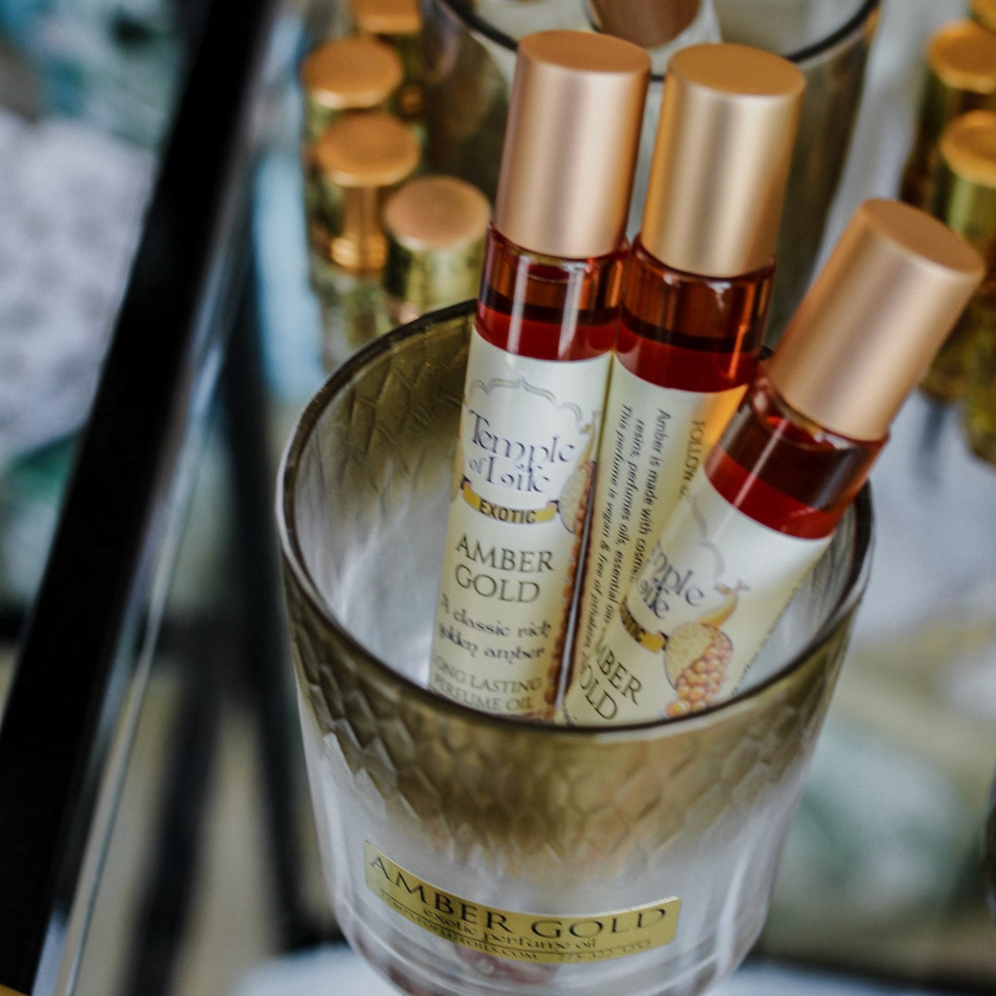 Bottles of 'Amber Gold' perfume with gold cap in a store display.