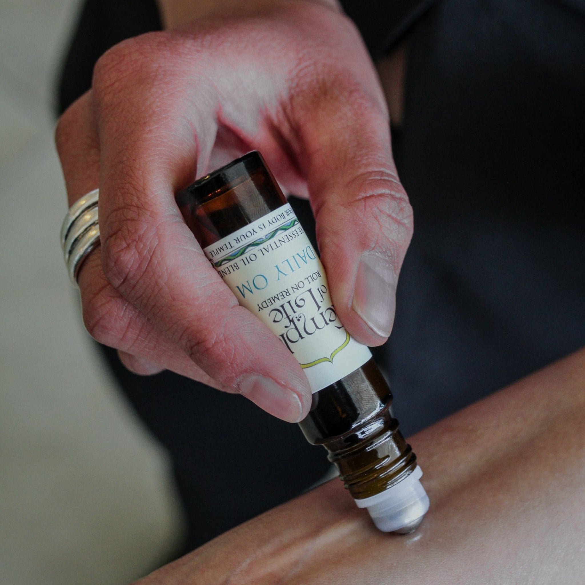 Hand applying a roll on bottle of essential oil to a wrist.