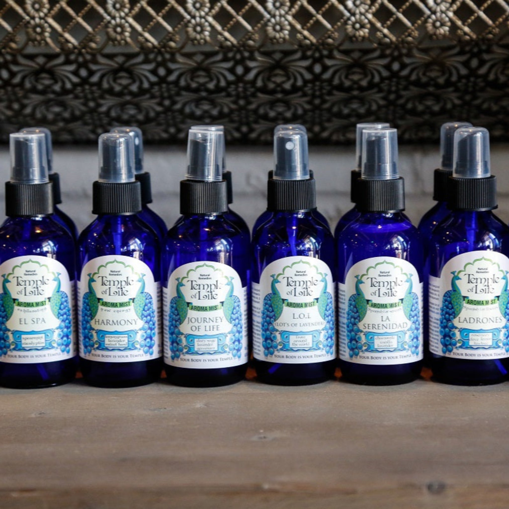 Row of blue bottle aroma mist sprays with labels on a wooden surface
