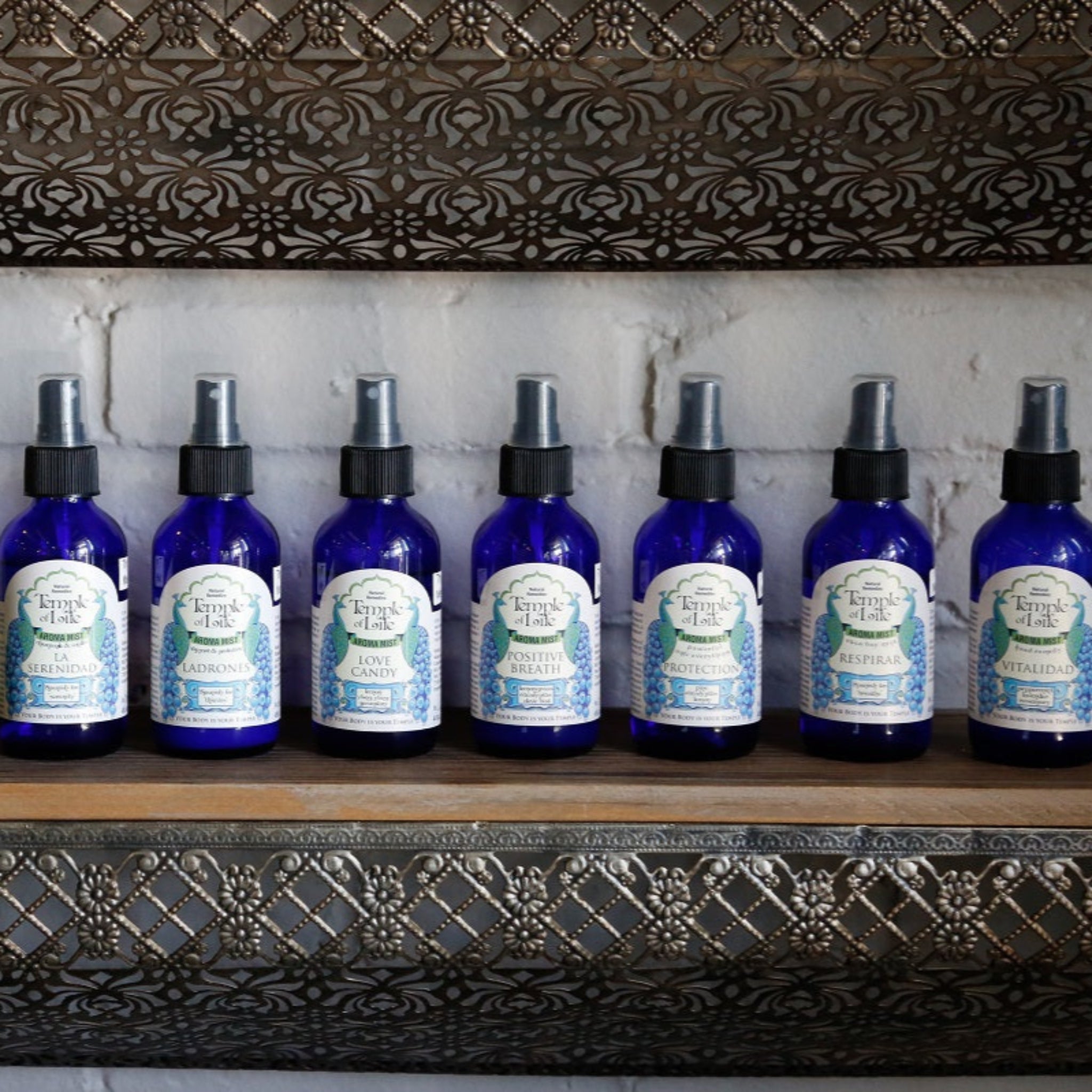 Row of aromatherapy with labels on a decorative shelf against a white brick wall.