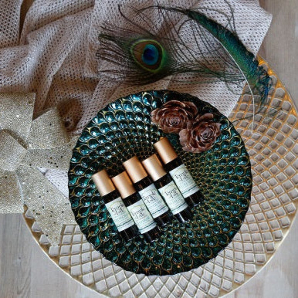 Set of holiday roll on bottles on a decorative tray with peacock feather.