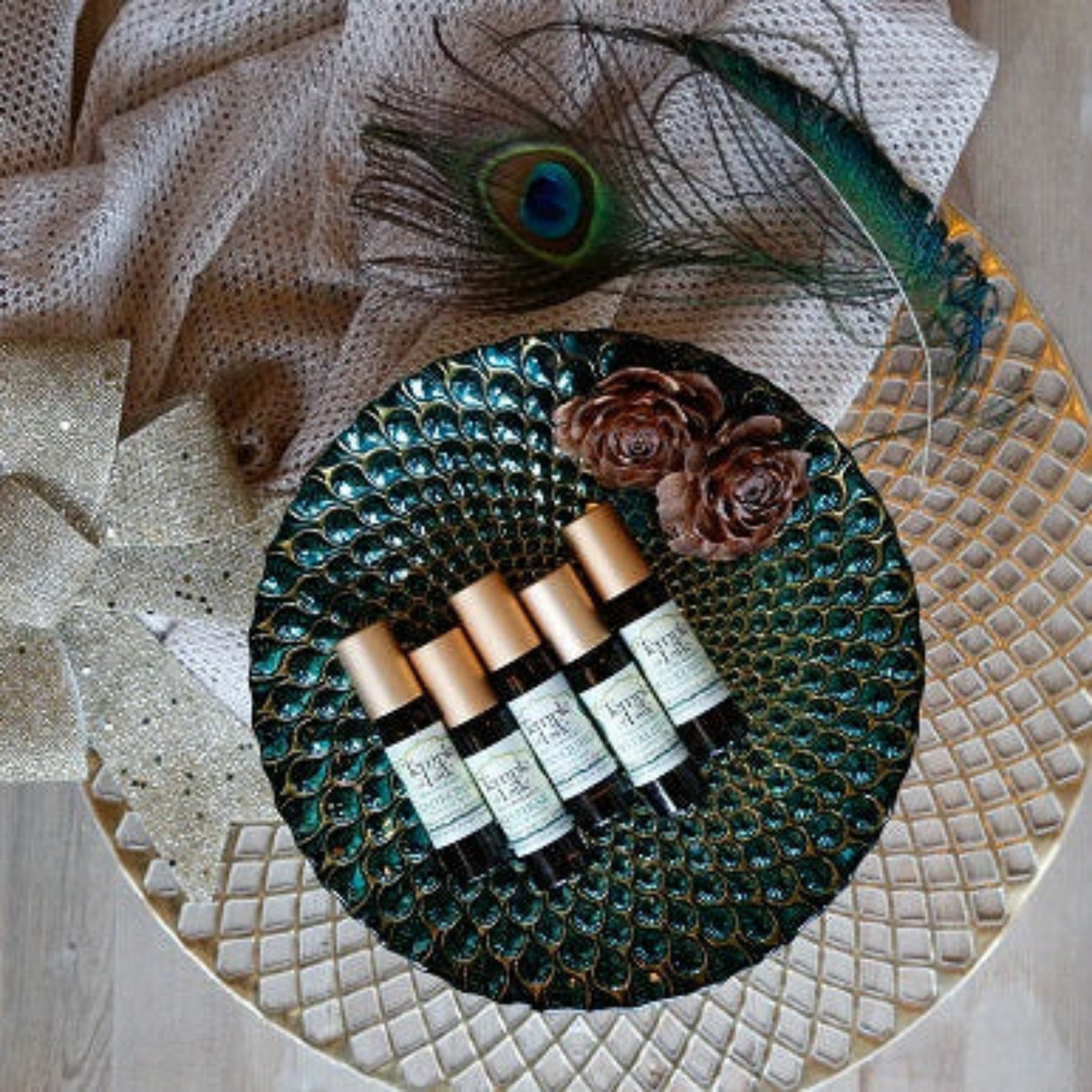Set of holiday roll on bottles on a decorative tray with peacock feather.